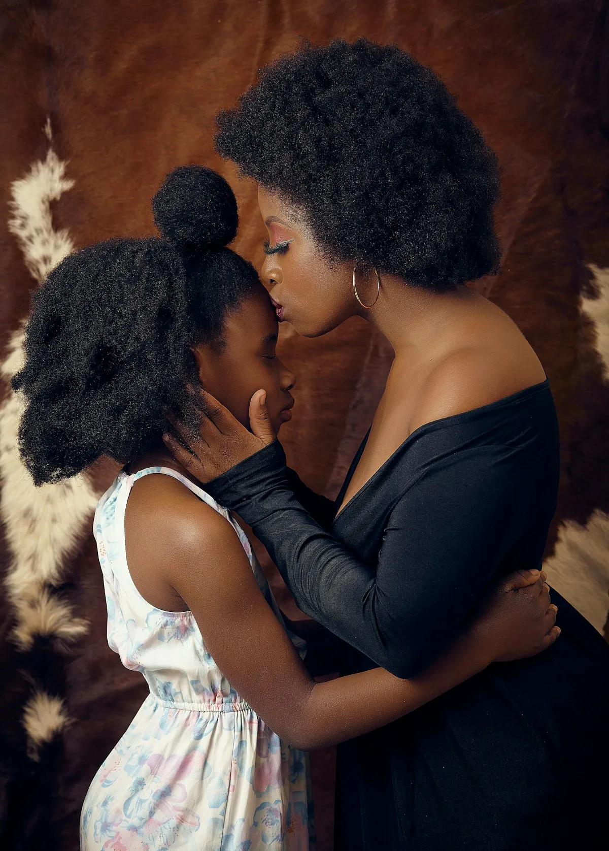 A mother tenderly kissing her young daughter’s forehead