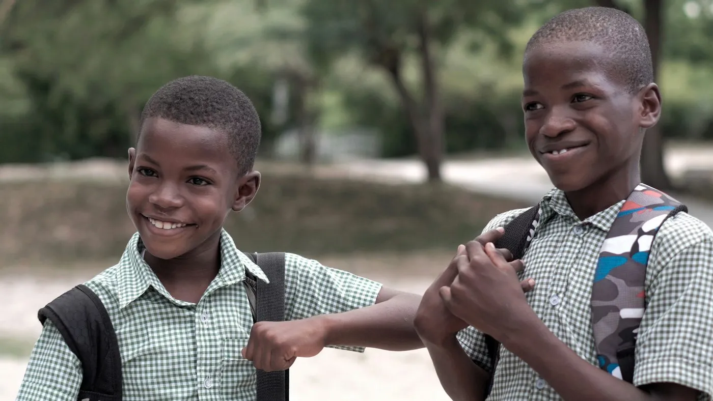 Two smiling schoolboys in uniform greeting each other